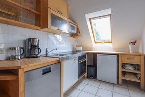 A compact kitchen with a dishwasher, microwave, and coffee maker.