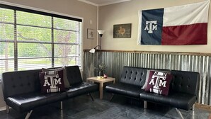A room with two black leather sofas, a small wooden table, and a large window.