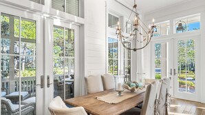 A dining area with a wooden table, white chairs, and a chandelier.