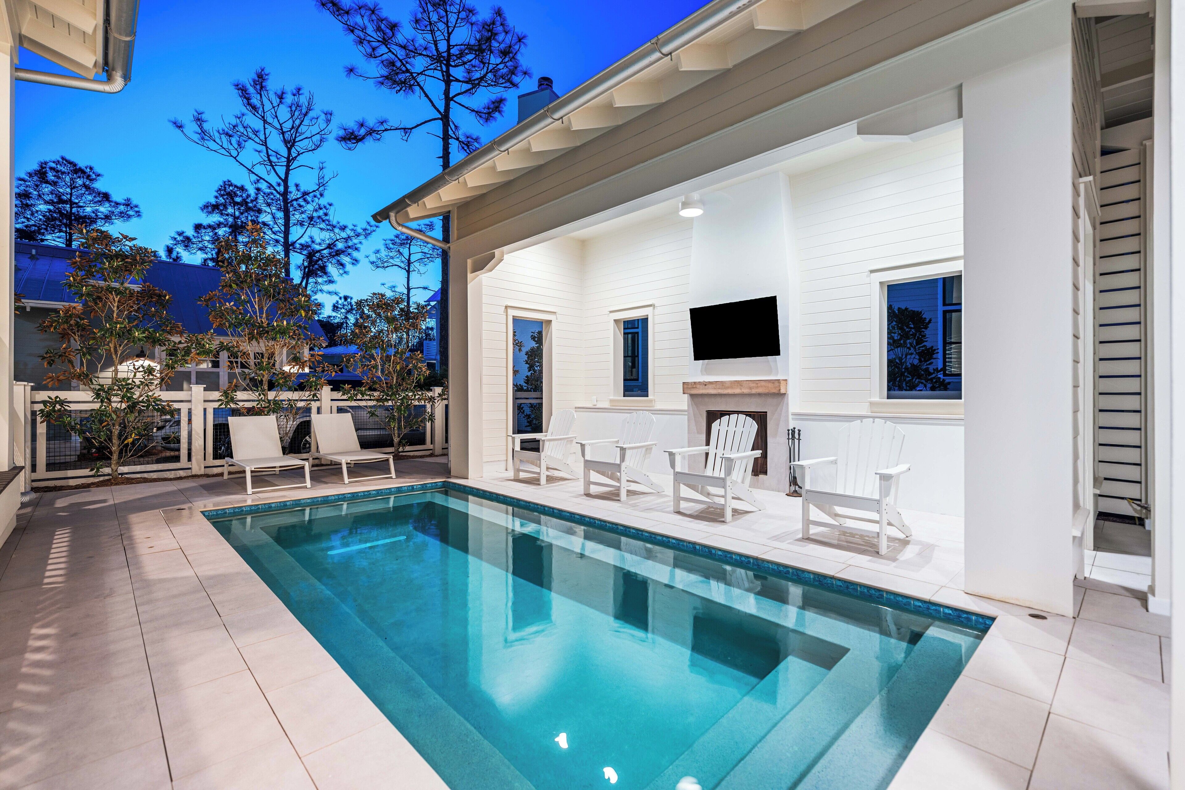 A modern outdoor pool area with a clear blue pool, white deck, and lounge chairs.