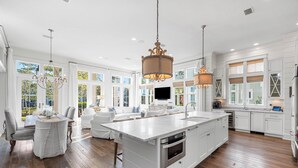 A spacious kitchen with white cabinetry, a large island, and pendant lighting.