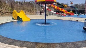 A water park with a central pool, slides, and a large umbrella structure.