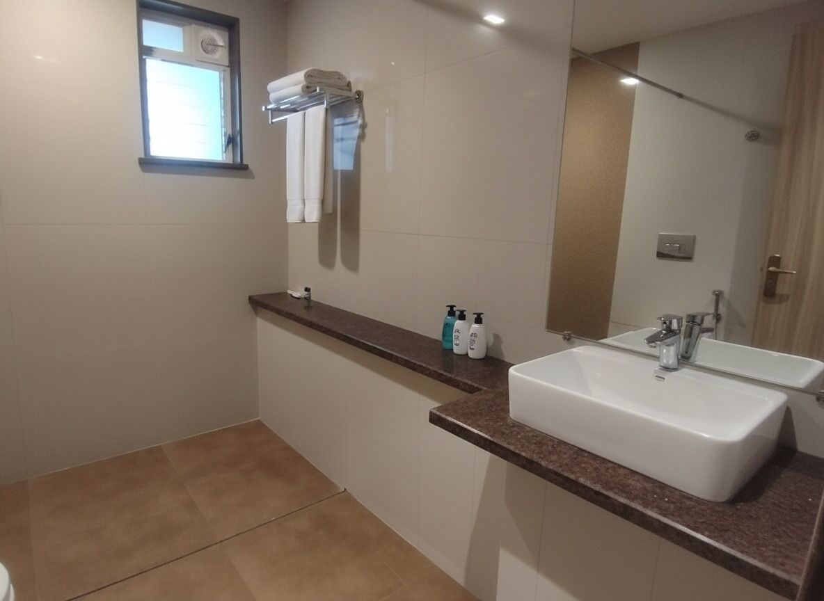 Un baño con dos lavamanos, un espejo y una ventana.