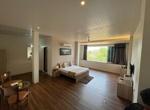 Une chambre d’hôtel moderne dotée d’un grand lit, d’un coin repas et d’une fenêtre avec des rideaux.