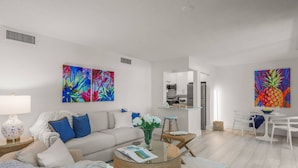 A modern living room with a sofa, coffee table, and artwork. - Sandy Cove Hideaway: Private, End-Unit, Walk to Village, Private Beach, Fishing Pier & Dog Friendly! (Siesta Key)