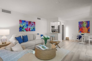 A modern living room with a sofa, coffee table, and artwork. - Sandy Cove Hideaway: Private, End-Unit, Walk to Village, Private Beach, Fishing Pier & Dog Friendly! (Siesta Key)