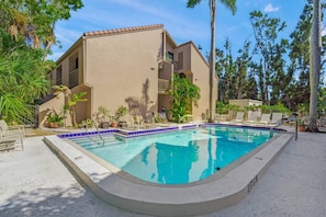 A swimming pool with lounge chairs and palm trees.