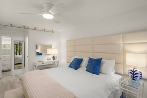 A hotel room with a bed, bedside tables, a ceiling fan, and a large window.