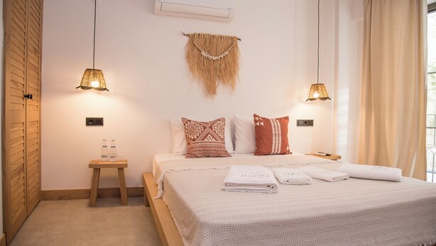 A neatly arranged bedroom with a bed, bedside tables, and a hanging macrame decoration. - Lupa Alacati (Cesme)