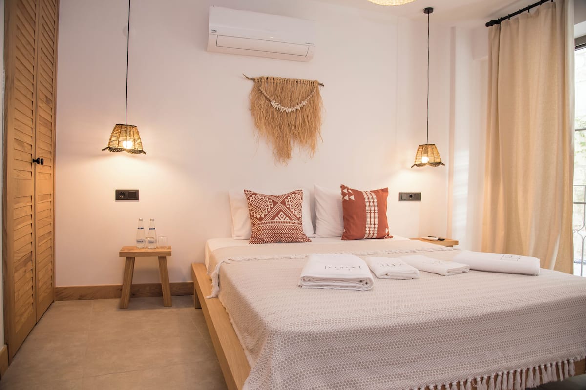 Un dormitorio ordenado con cama, mesitas de noche y una decoración de macramé colgante.