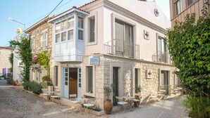 A stone building with a sign 'LUPA' on the front. It has a balcony with metal railings and a door with a blue frame. - Lupa Alacati (Cesme)