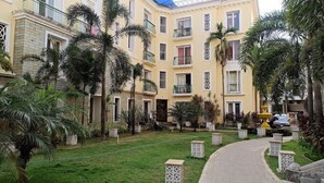 Ein Innenhof mit einem gepflasterten Weg, Palmen und einem Gebäude mit Balkonen und Fenstern.