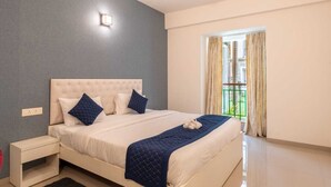 Ein Schlafzimmer mit einem großen Bett, einem Nachttisch, einer Wandleuchte und einem Fenster mit Vorhängen.
