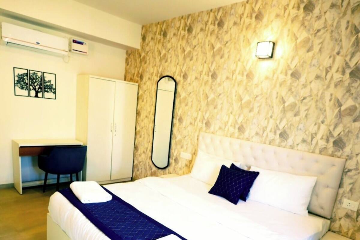 Une chambre moderne avec un grand lit, un ventilateur de plafond, un bureau et une armoire.