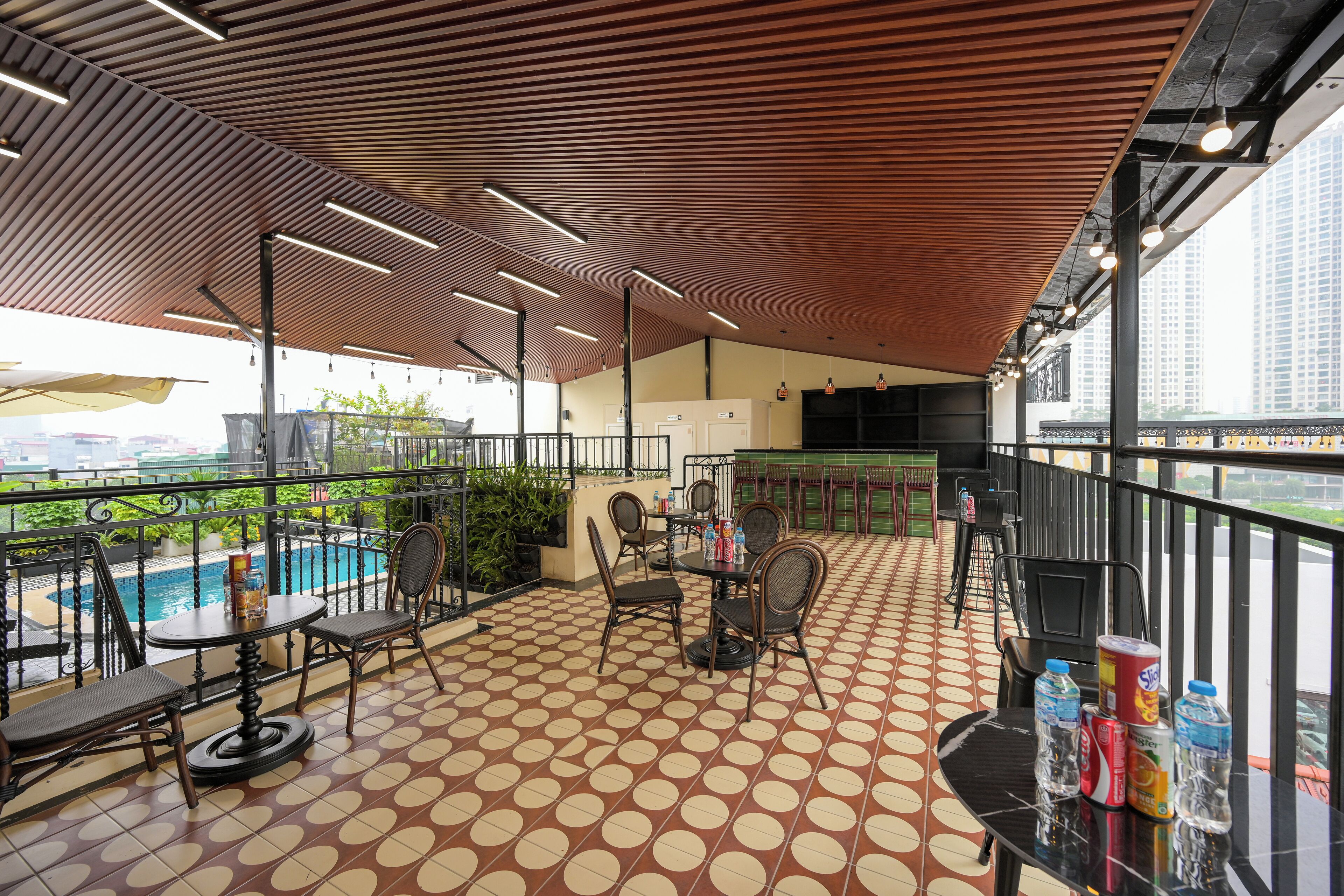 A rooftop bar with a pool view, outdoor seating, and a patterned floor.