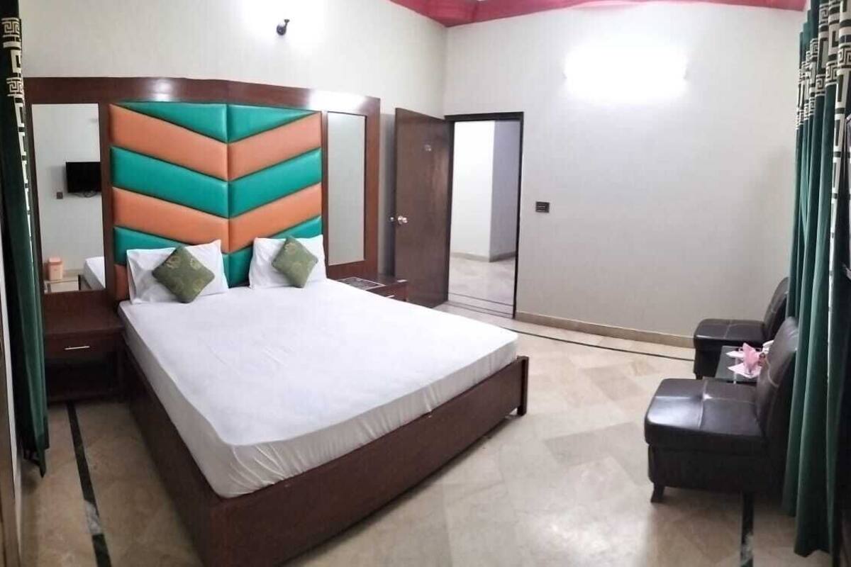 A bedroom with a bed, a chair, a TV, and a wardrobe.