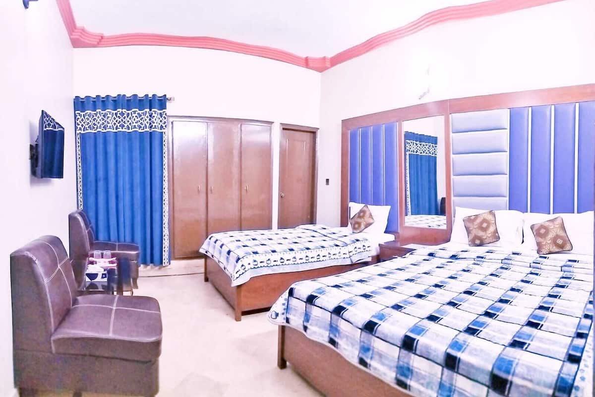 A hotel room with two beds, a sofa, a desk, and a wardrobe.