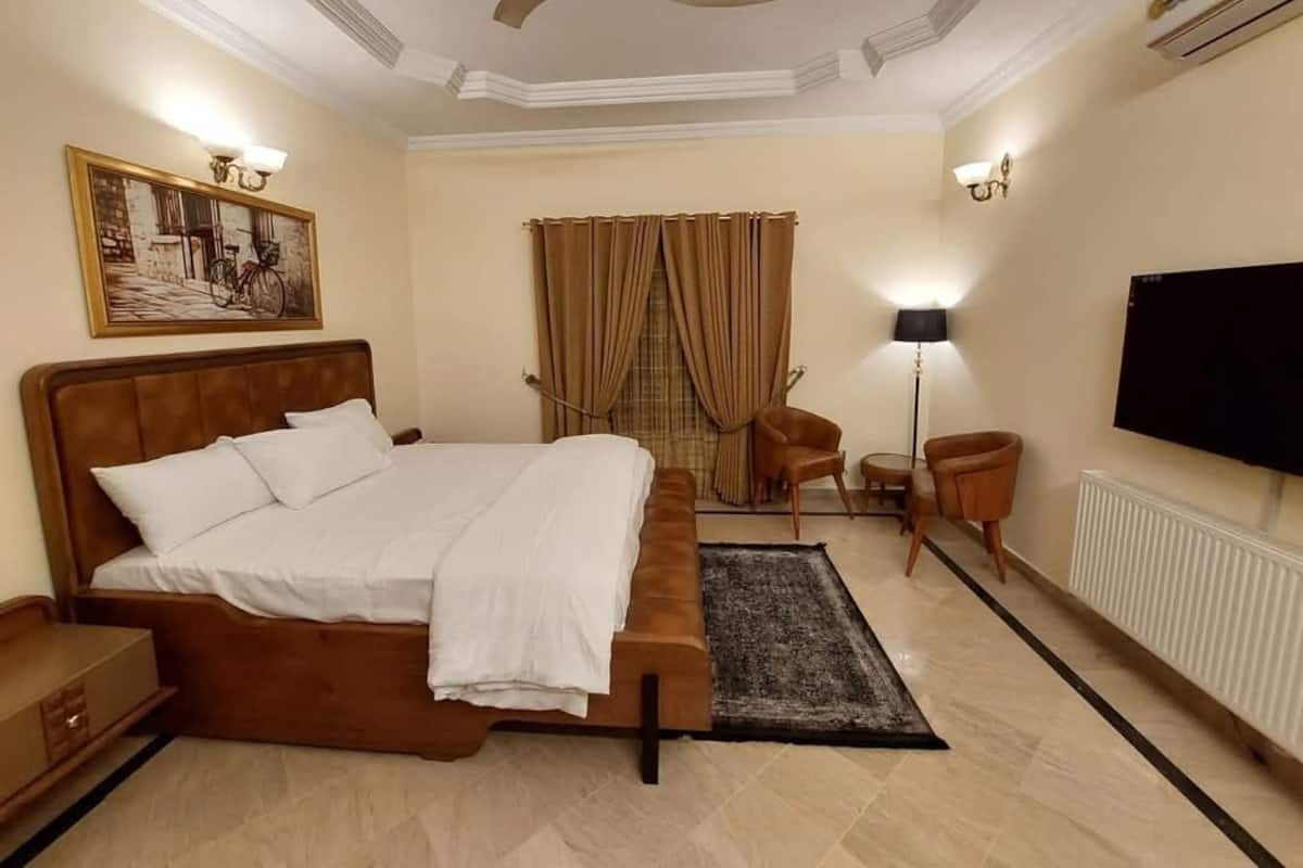 A hotel room with a large bed, a ceiling fan, a television, a desk, and a chair.