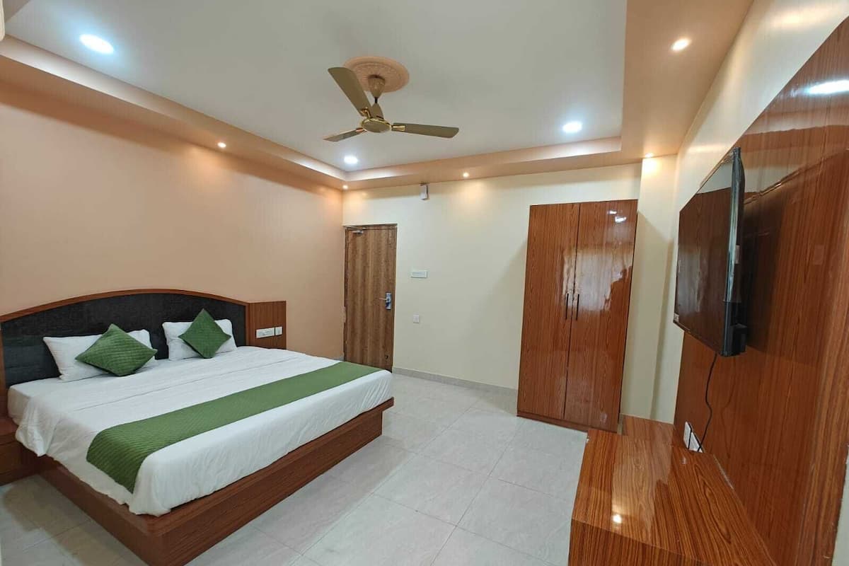 A bedroom with a bed, a ceiling fan, a wardrobe, and a TV.