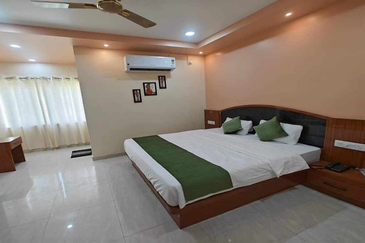 A hotel room with a bed, bedside table, and a desk with a chair.