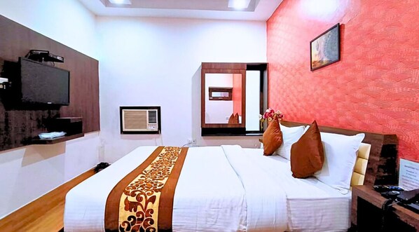 Une chambre d’hôtel avec un grand lit, un téléviseur à écran plat, un miroir et un mur rouge à texture.