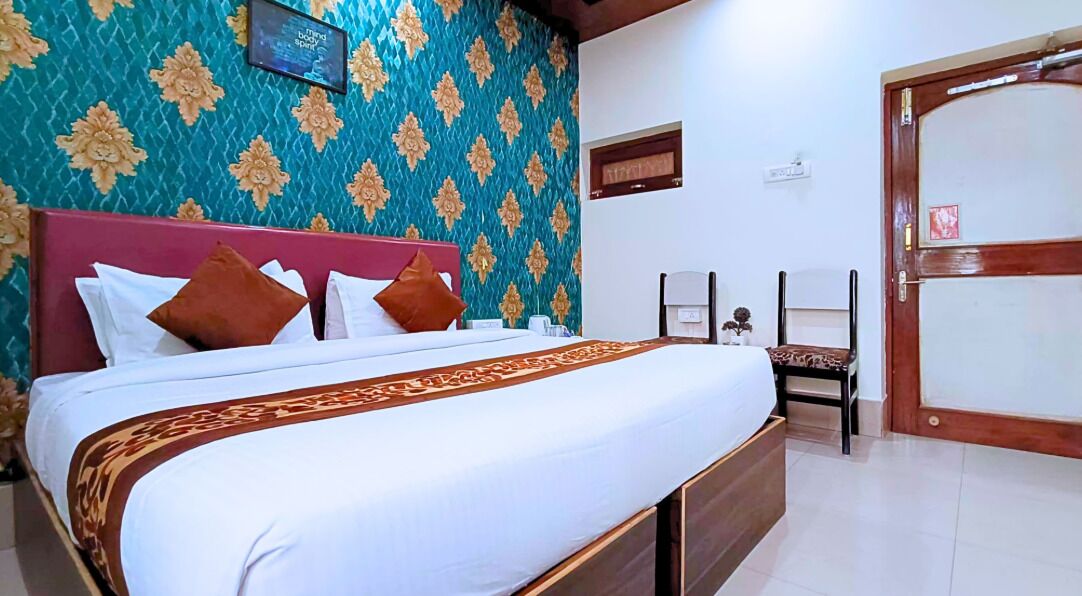 Una cama bien hecha con una colcha estampada, cabecera de madera y una pared decorada con estampado floral.