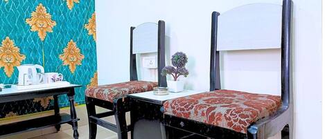 Una habitación con dos camas individuales, una mesita con un hervidor y una silla.