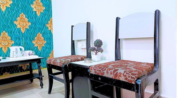 A room with two single beds, a small table with a kettle, and a chair.