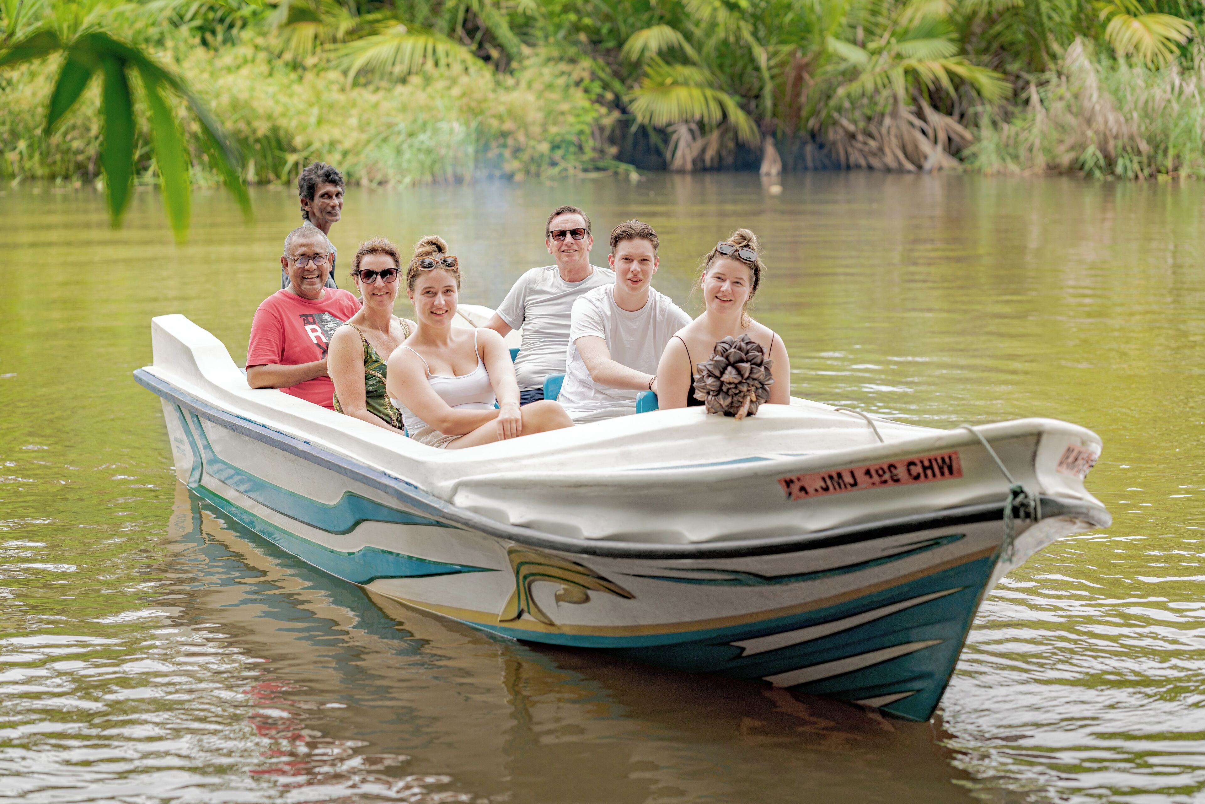A boat with people on it, surrounded by water and greenery.