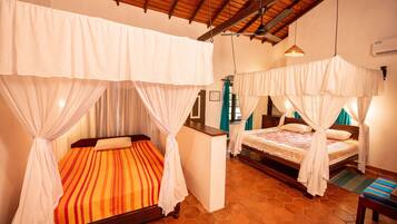 A hotel room with two beds, each with a canopy. The room has a tiled floor and a wooden ceiling.
