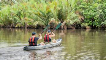 Two people in a canoe on a calm river surrounded by lush greenery.