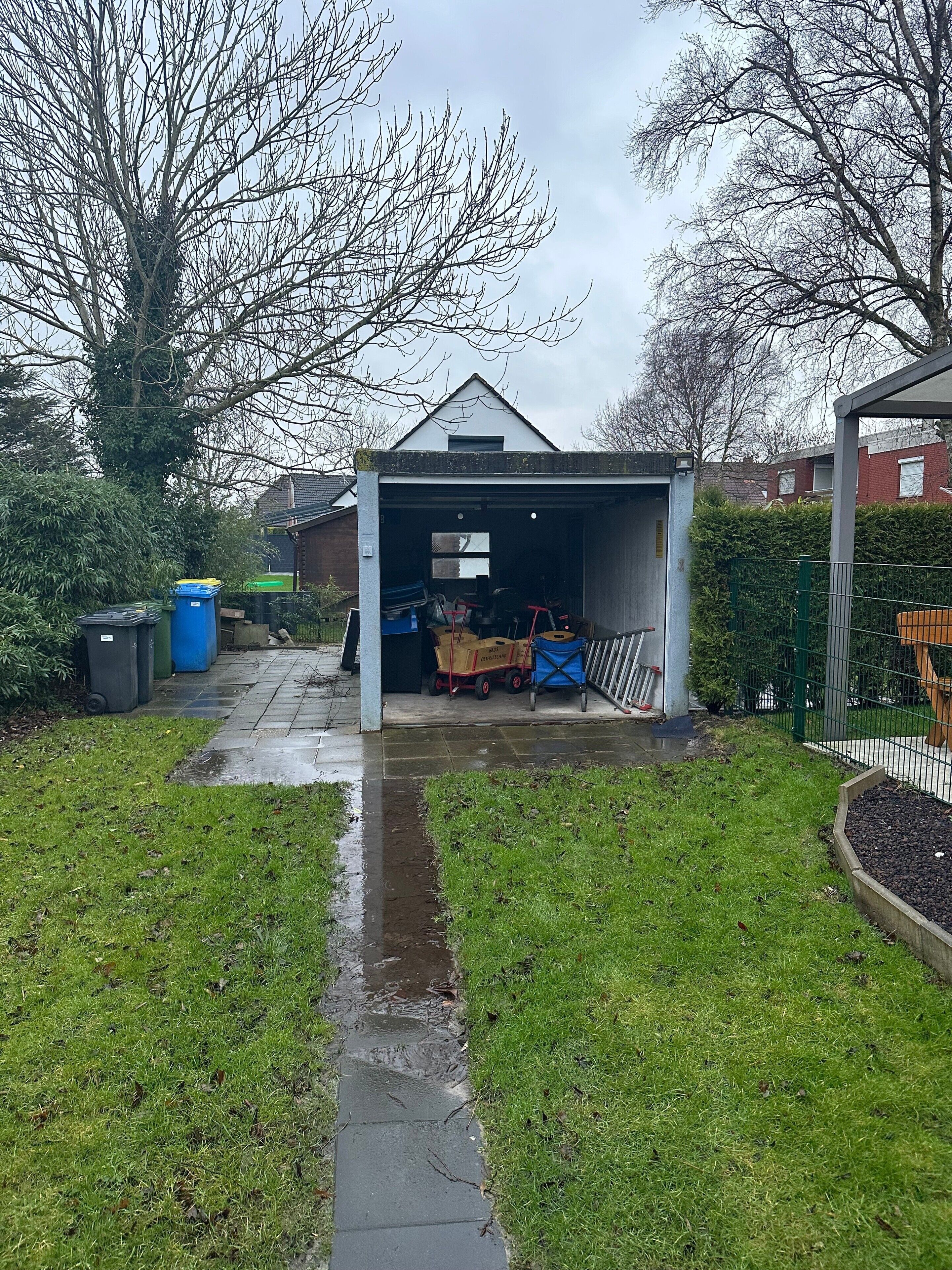 A garage with a covered entrance, a pathway leading to it, and a small garden area.