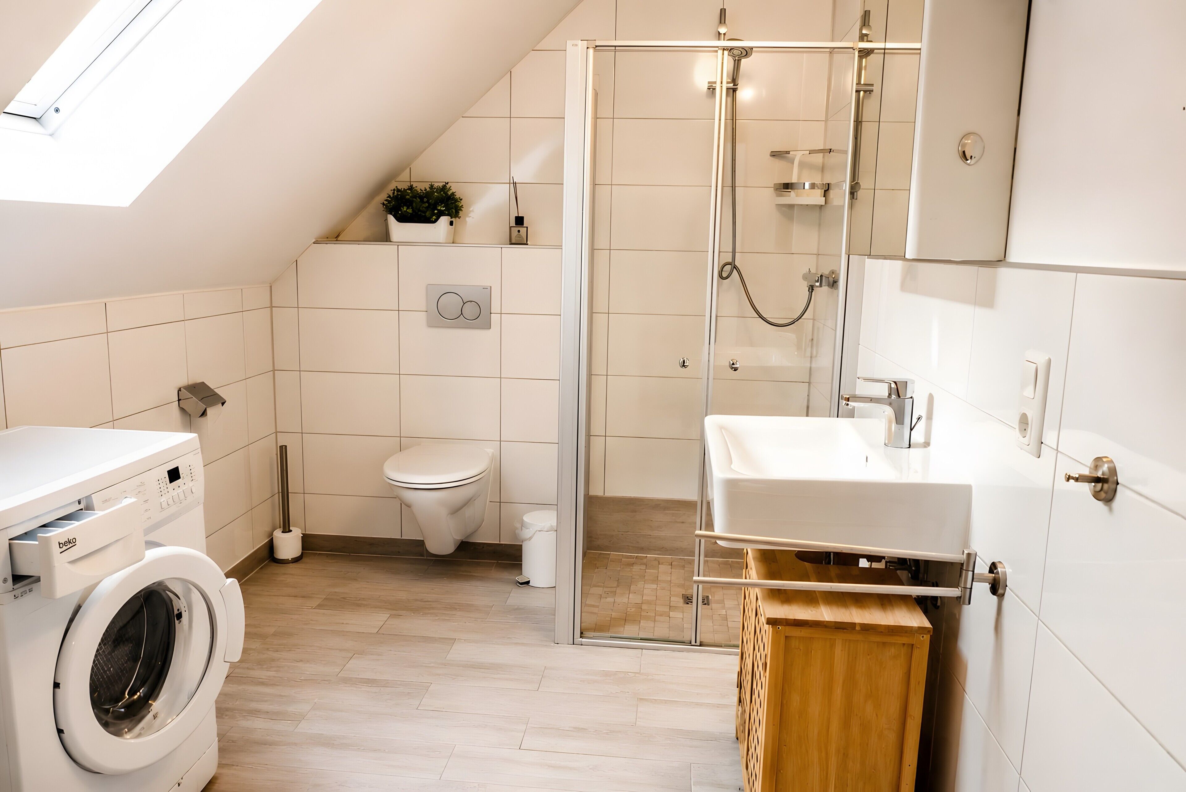 Ein modernes Badezimmer mit Waschmaschine, Toilette, Dusche und Waschbecken.