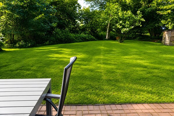 A well-maintained lawn with a patio area and a wooden table.