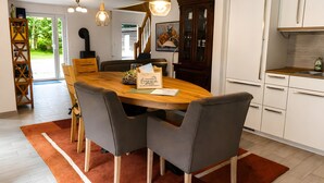 A dining area with a wooden table, grey chairs, and a red rug. - Holiday Home 'Birken' with Shared Garden and Wi-Fi (Hage)