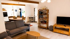 Un salon comprenant un canapé, une table basse, un meuble pour la télévision et une bibliothèque.