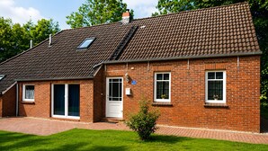 A brick house with a tiled roof, a front door, and a small garden. - Holiday Home 'Birken' with Shared Garden and Wi-Fi (Hage)