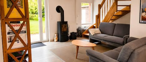 A living room with a sofa, a coffee table, a wooden bookshelf, a fireplace, and a staircase.