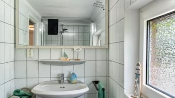 A bathroom with a white sink, mirror, and tiled walls.