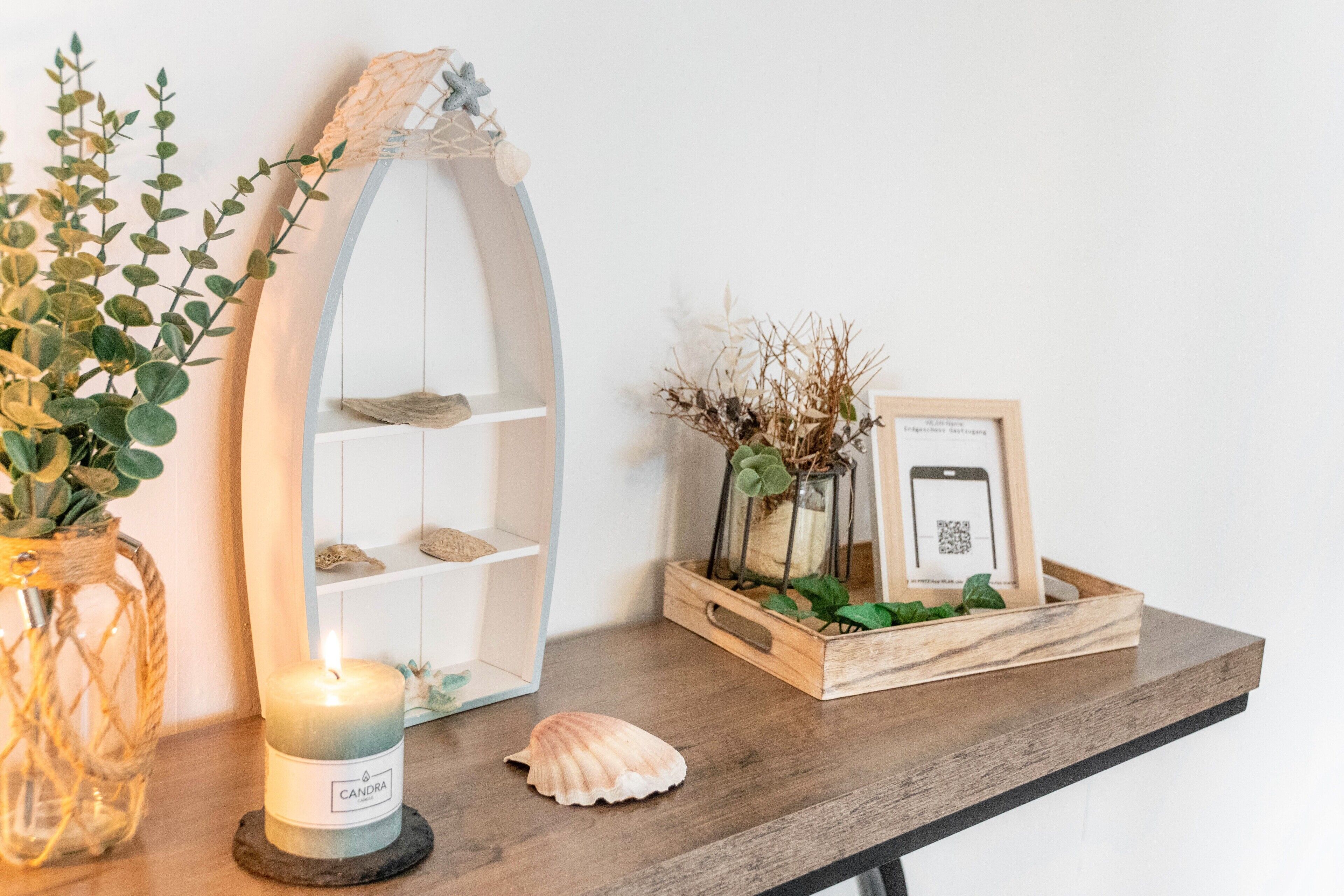 A wooden shelf with a candle, a seashell, and a framed photo.