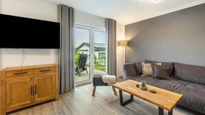 A modern living room with a sofa, wooden cabinet, and a flat-screen TV. - Holiday Home 'Diemelblick' with Lake View, Private Terrace and Wi-Fi (Diemelsee)