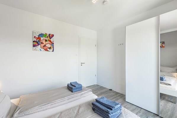 Un dormitorio moderno con una cama, una puerta y un espejo.