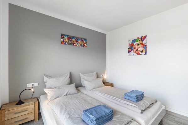 A bedroom with a bed, bedside tables, and two wall-mounted artworks.