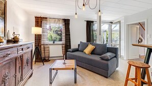 Un salon comprenant un canapé, une table basse, un meuble et une lampe.
