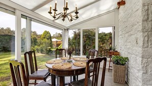 Une véranda équipée d’une table à manger, de chaises et d’un lustre.