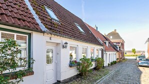Een rij traditionele Europese huizen met schuine daken, een geplaveid straatje en een heldere lucht.