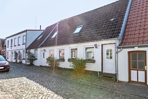 Une rangée de maisons de style européen traditionnel, avec des toits inclinés, une rue pavée et une voiture garée.