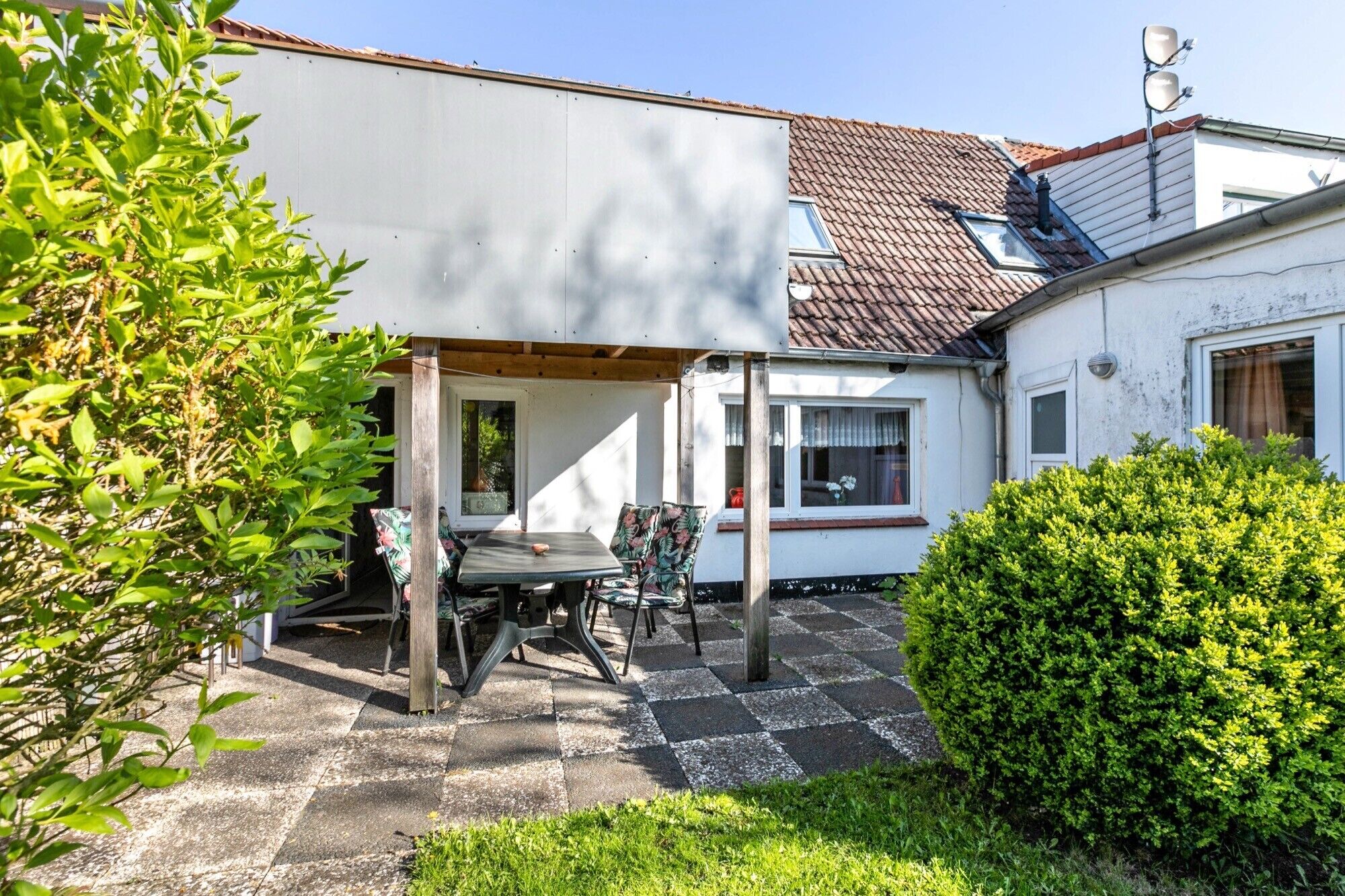 Il s’agit d’une propriété résidentielle dotée d’un patio couvert, d’un petit jardin et d’un mur extérieur peint en blanc.