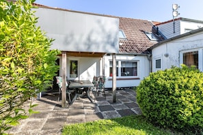 Il s’agit d’une propriété résidentielle dotée d’un patio couvert, d’un petit jardin et d’un mur extérieur peint en blanc.