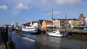 Een haven met aangemeerde boten, een brug op de achtergrond en kleurrijke gebouwen langs de waterkant.